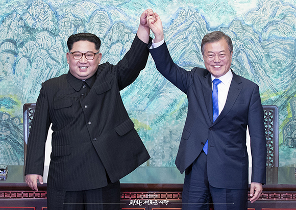 문재인 대통령과 김정은 위원장이 2018년 4월 27일 ‘판문점 선언문’에 서명한 뒤 손을 들어 보이고 있다. (사진공동취재단)