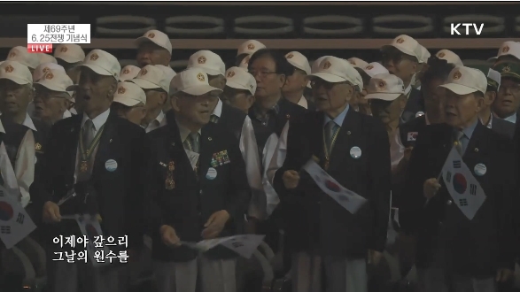 25일 서울 중구 장충체육관에서 열린 6·25 전쟁 69주년 기념 행사에 참석한 6·25 참전 유공자들이 태극기를 흔들며 6·25의 노래를 부르고 있다. (사진출처: KTV국민방송 뉴스영상 캡처)