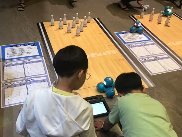 2019 과학학습 교구 박람회에서 대시를 활용한 볼링 게임 워크숍에 참가한 아이들이 대시 전용앱인 블록클리를 활용한 코딩으로 대시를 움직여 볼링 공을 쓰러뜨리는 활동 체험을 하고 있다